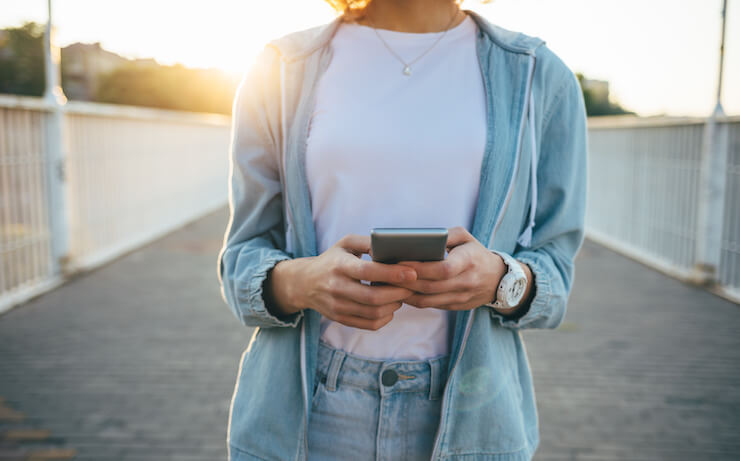 Woman wearing her cell phone outside during sunset